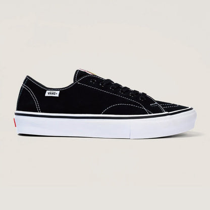A black Vans platform sneaker with a thick white sole, white contrast stitching, and a small white Vans side tag, shown against a light beige background.