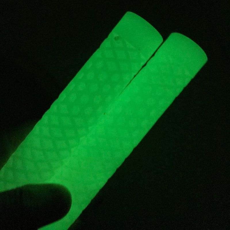 Two glowing green stick-like products with a textured surface, held against a dark background.