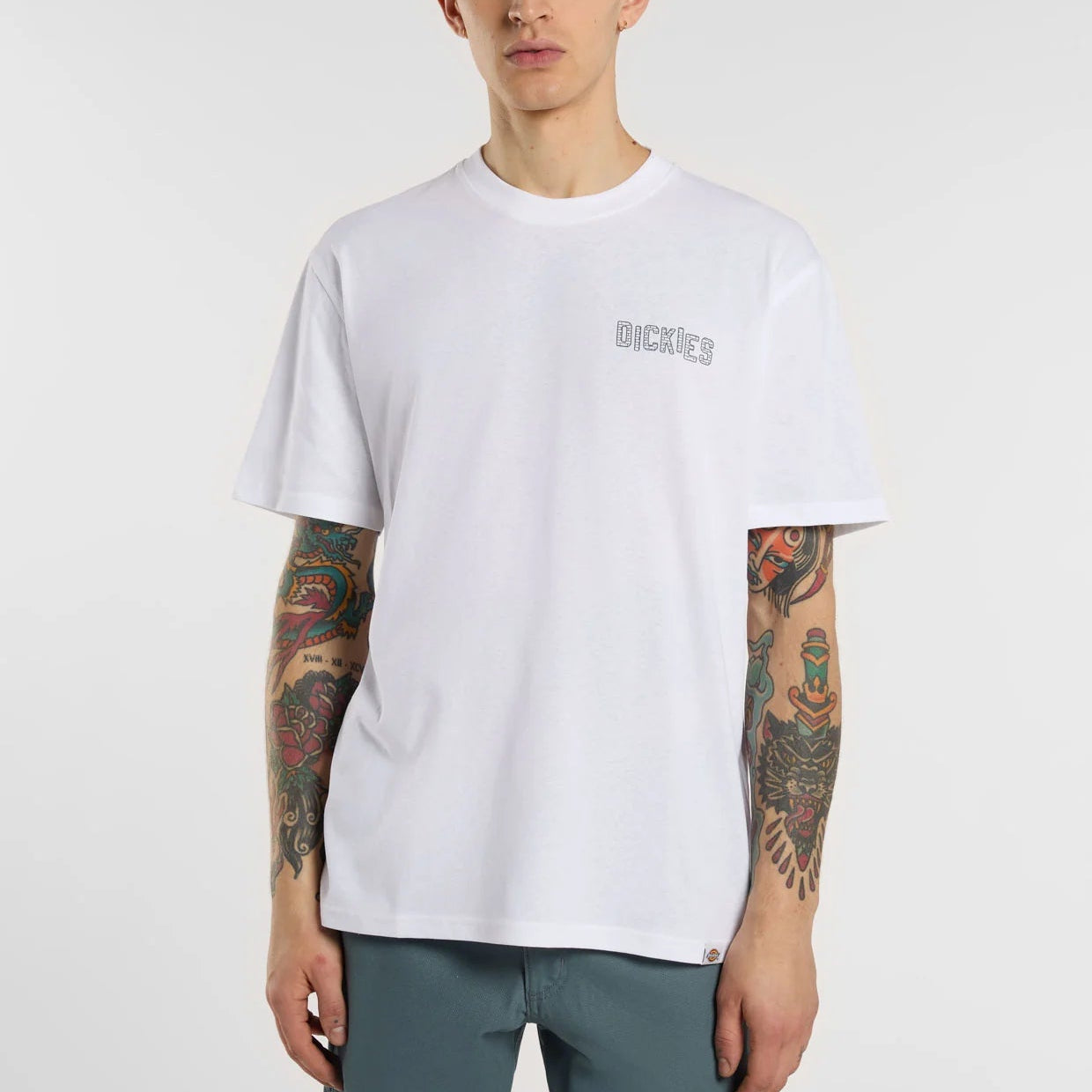 Person wearing a white t-shirt with a brand logo on a plain background