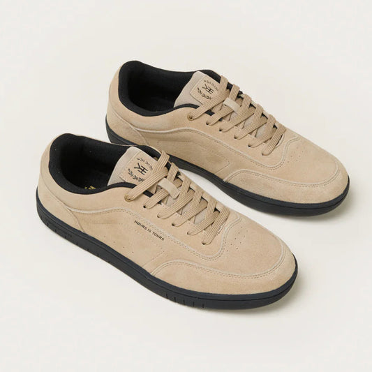 Pair of beige sneakers with black soles on a light gray background