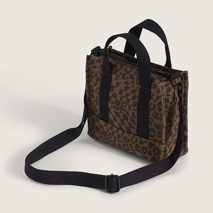 Leopard print bag with black straps on a light beige background