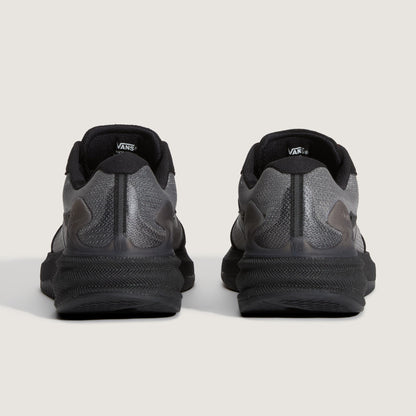 A pair of Vans sneakers shown from the back, featuring a dark gray and black colorway with textured mesh and synthetic overlays on a light gray background.