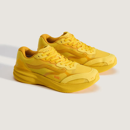 A pair of yellow athletic sneakers with a mesh upper and thick sculpted sole, photographed on a clean light gray studio background.