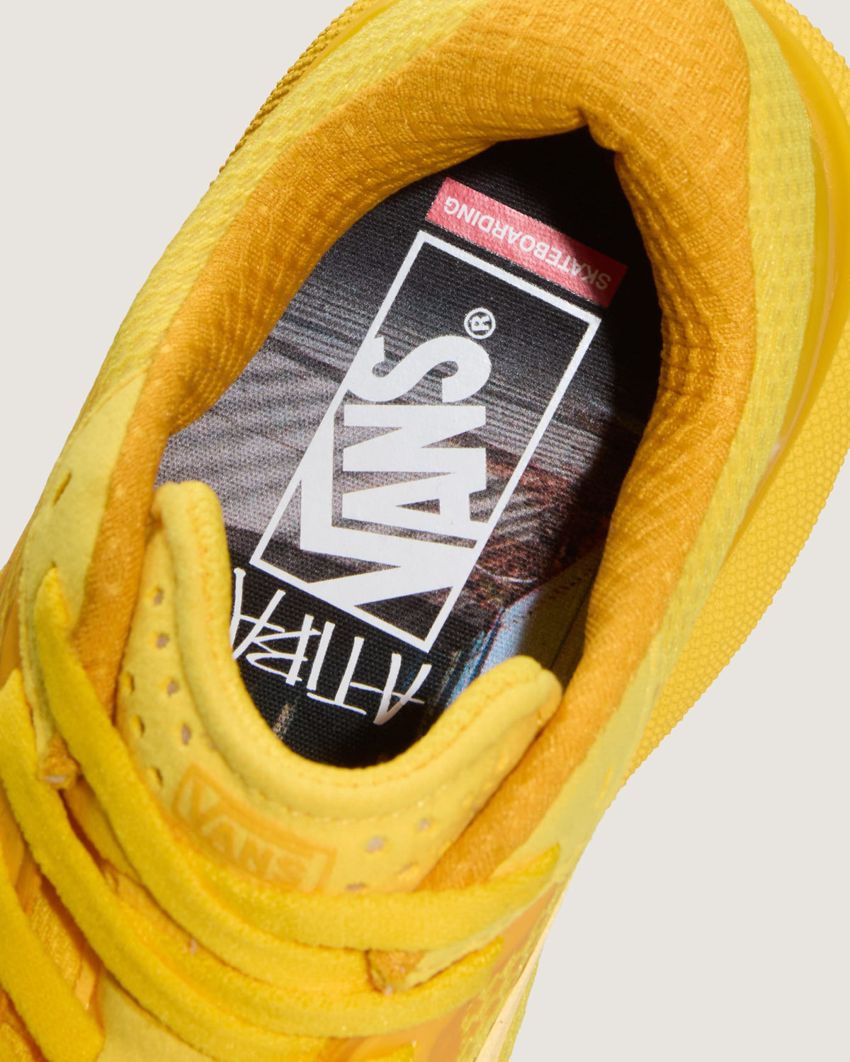Close-up of a yellow Vans sneaker showing the interior lining, tongue, and branded insole with the Vans logo.