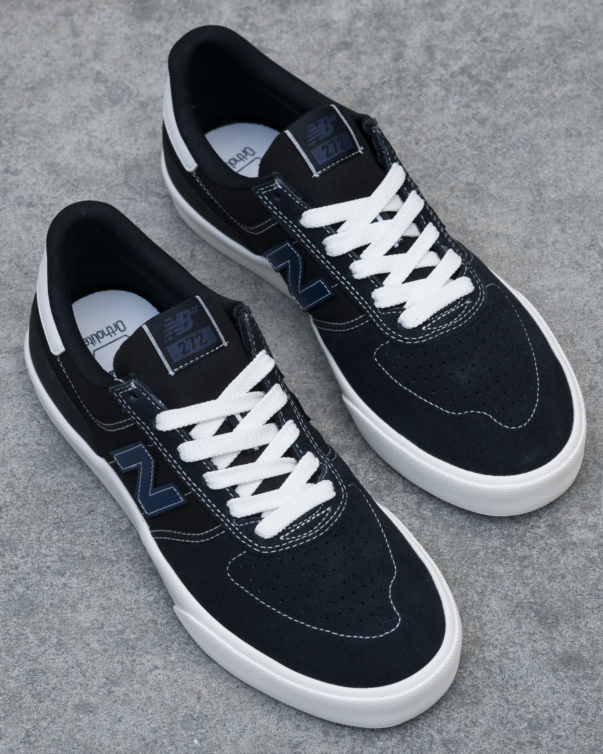 Black sneakers with white laces on a gray concrete surface