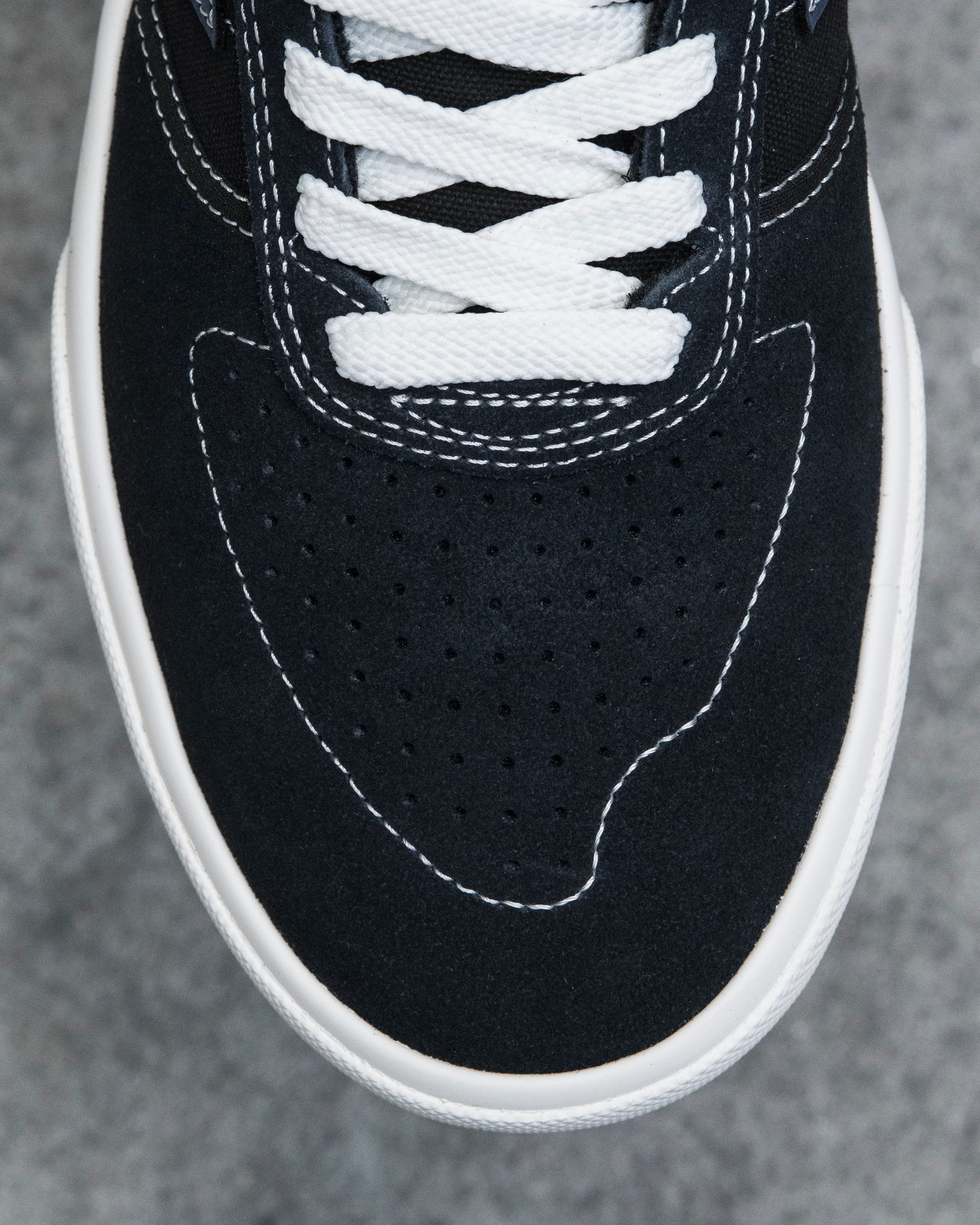 Close-up of a black sneaker with white laces on a gray background