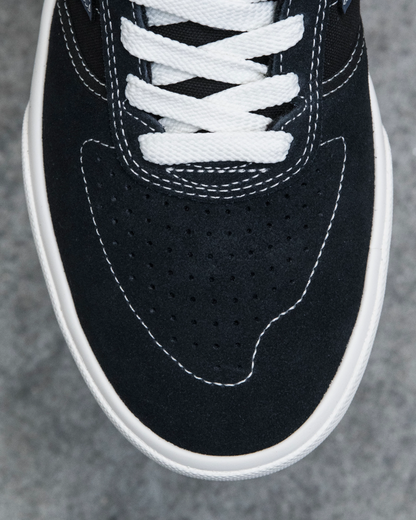 Close-up of a black sneaker with white laces on a gray background