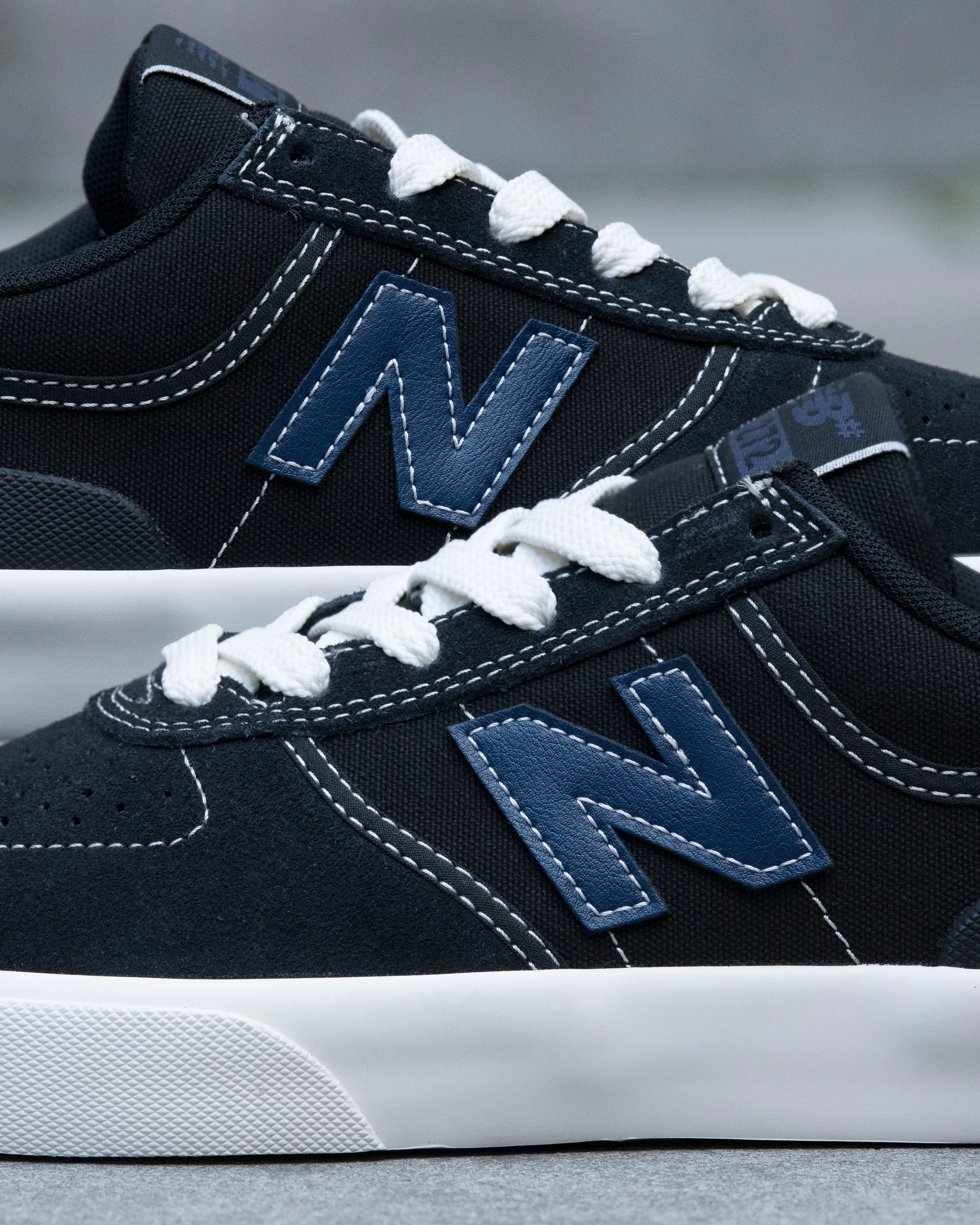 Close-up of navy blue sneakers with white laces and New Balance logo on a blurred background