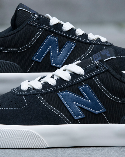 Close-up of navy blue sneakers with white laces and New Balance logo on a blurred background