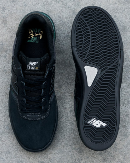 Black New Balance sneaker shown from top and bottom on a gray concrete surface