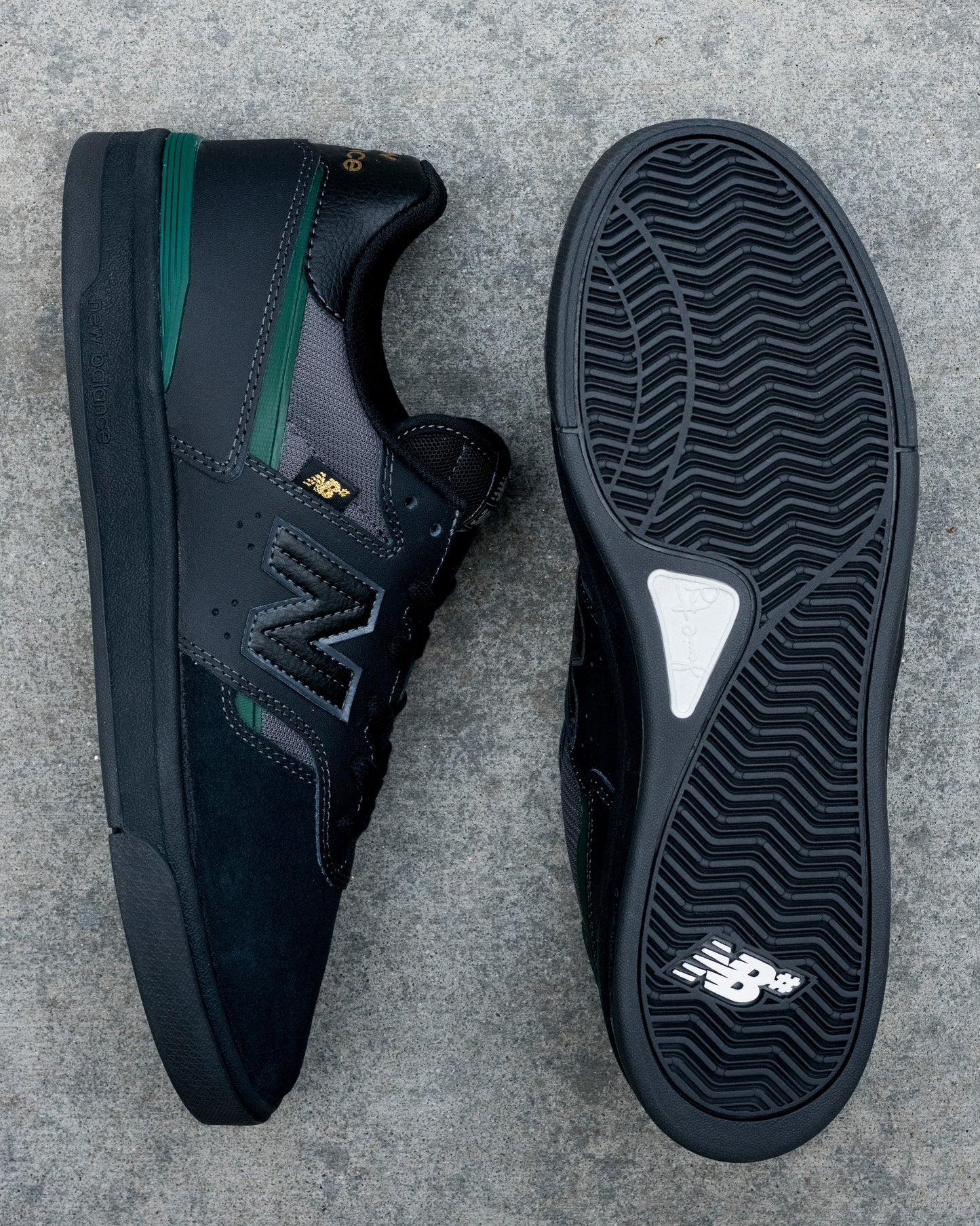 Black New Balance sneakers on a gray concrete surface