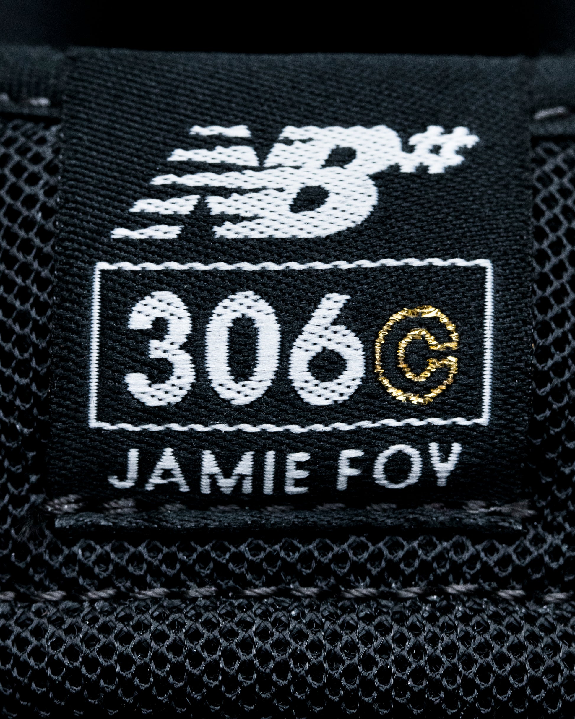 Close-up of a New Balance label with '306 C Jamie Foy' on a black background