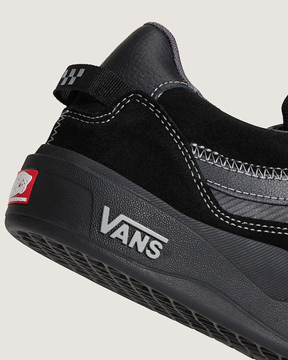 Black Vans shoe with a white logo on a light gray background