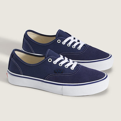 Pair of navy blue sneakers with white laces on a light gray background