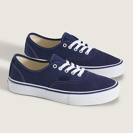 Pair of navy blue sneakers with white laces on a light gray background