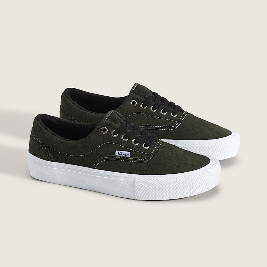 A pair of Vans low-top platform sneakers in dark olive green canvas with white platform soles and black laces, displayed on a light beige background.