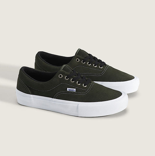 A pair of Vans low-top platform sneakers in dark olive green canvas with white platform soles and black laces, displayed on a light beige background.