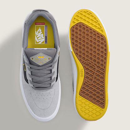 A pair of Vans Old Skool sneakers shown from a top-down view, with one shoe displaying the light gray suede and gray leather upper, and the other showing the yellow and brown textured Vans sole.