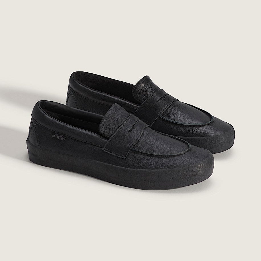 Pair of black loafers on a light beige background