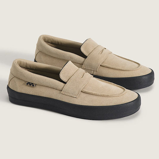 Pair of beige loafers with black soles on a light gray background
