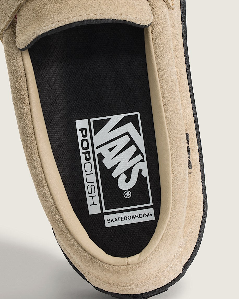 Close-up of a tan slip-on shoe with Vans logo on a black insole.