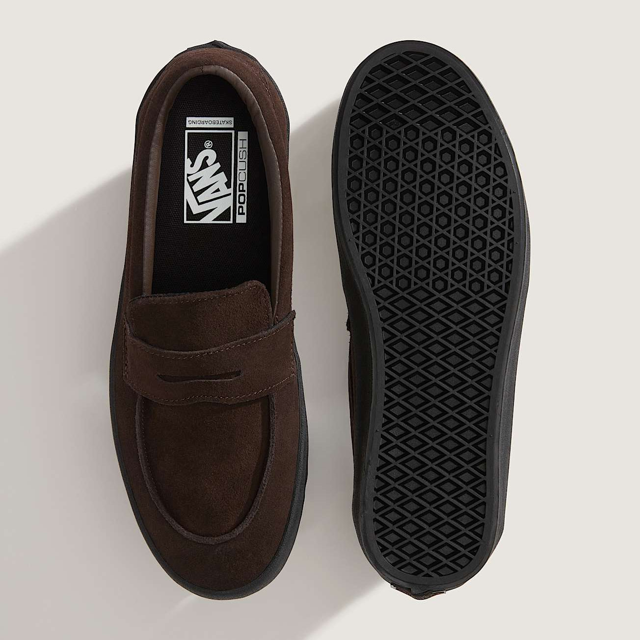 Brown loafer shoe with black sole on a light gray background