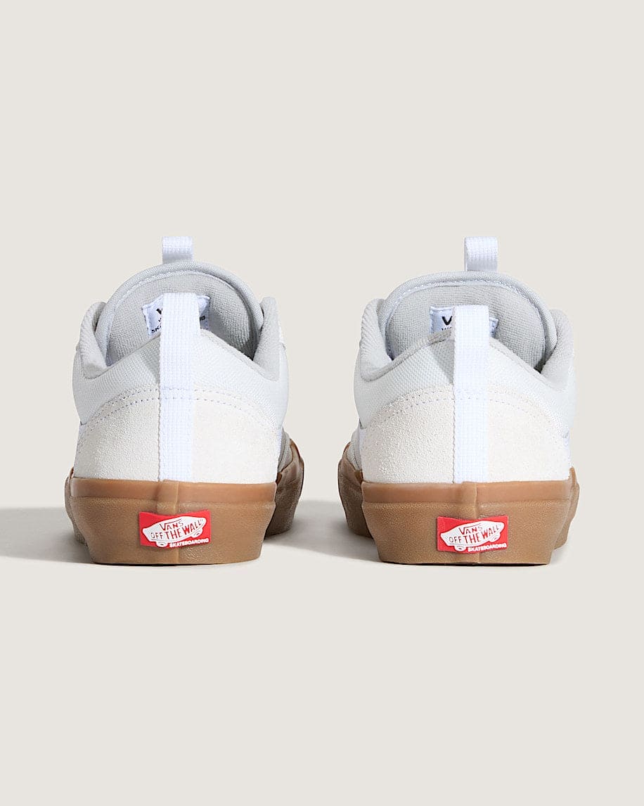 Pair of white sneakers with brown soles on a beige background