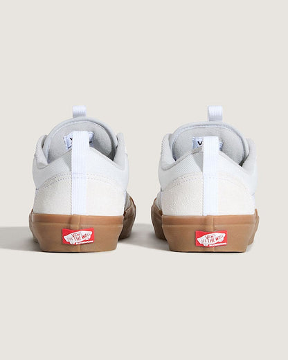 Pair of white sneakers with brown soles on a beige background