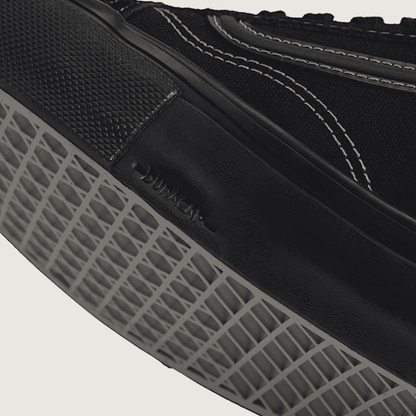 Close-up of a black sneaker with Duraflex sole on a light background