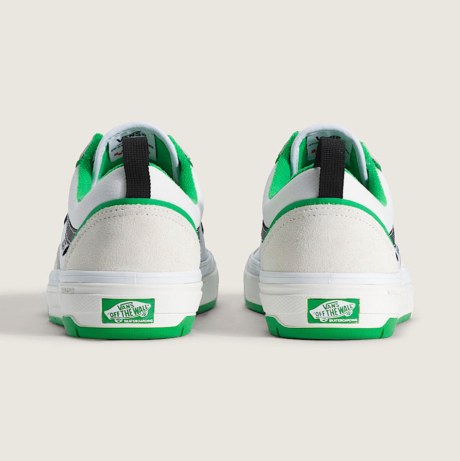 White sneakers with green accents and visible brand logo on a light beige background