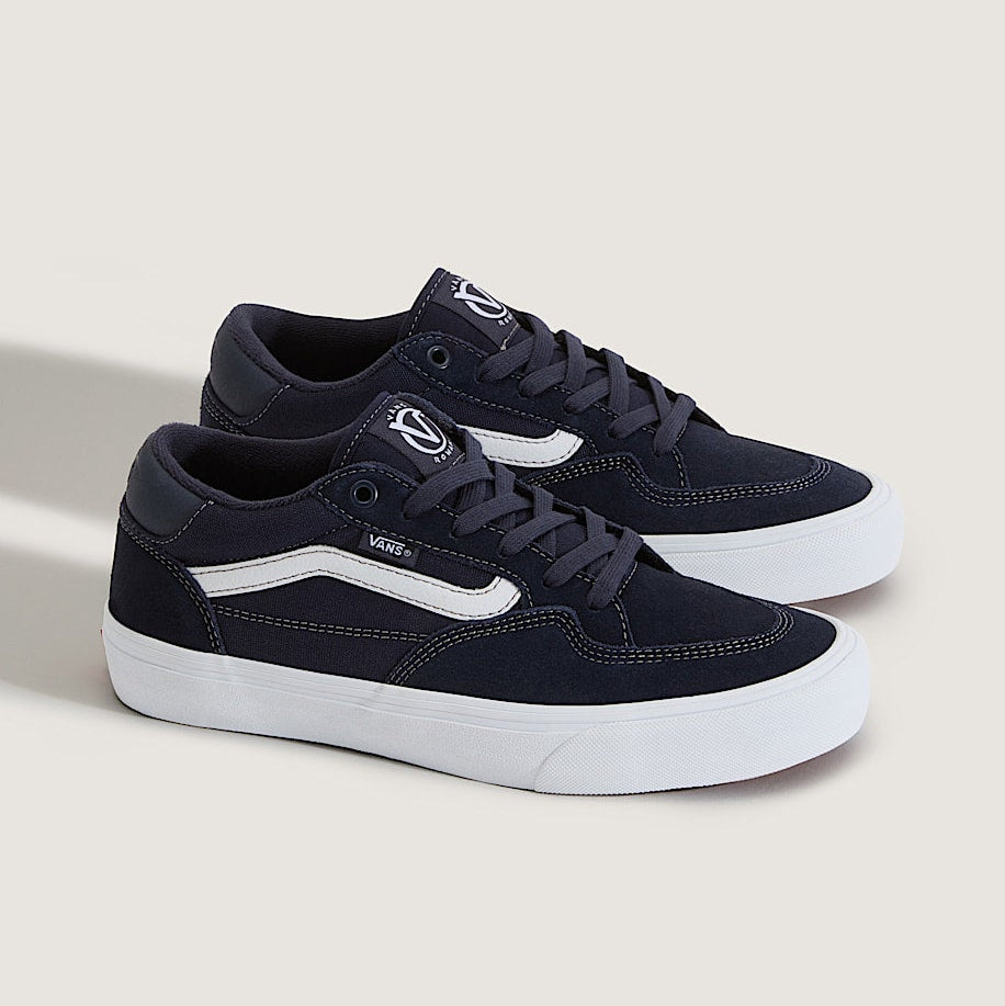 Navy blue sneakers with white soles on a beige background