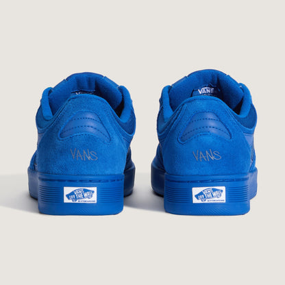 A pair of Vans low-top sneakers shown from the back, featuring a vibrant blue suede and synthetic leather upper with matching blue rubber soles and white Vans logo patches on the heel.