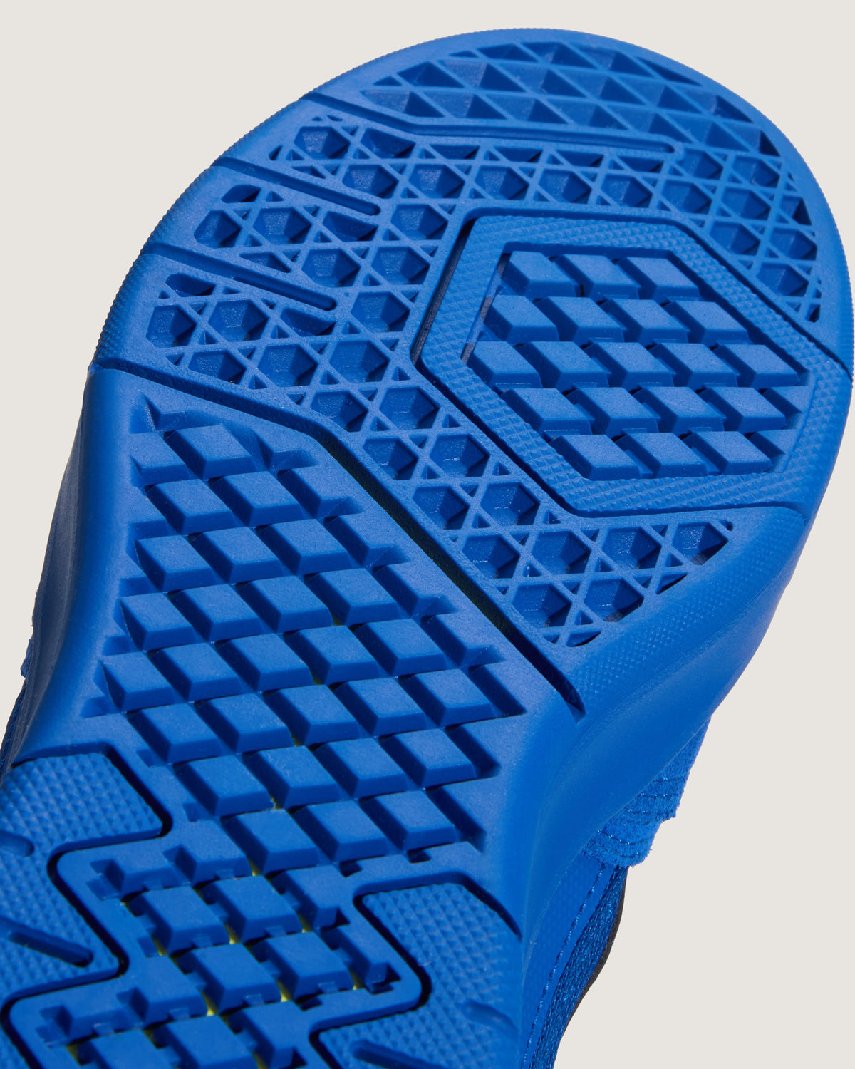 Close-up of a bright blue athletic shoe sole showing textured tread patterns on a light gray background.