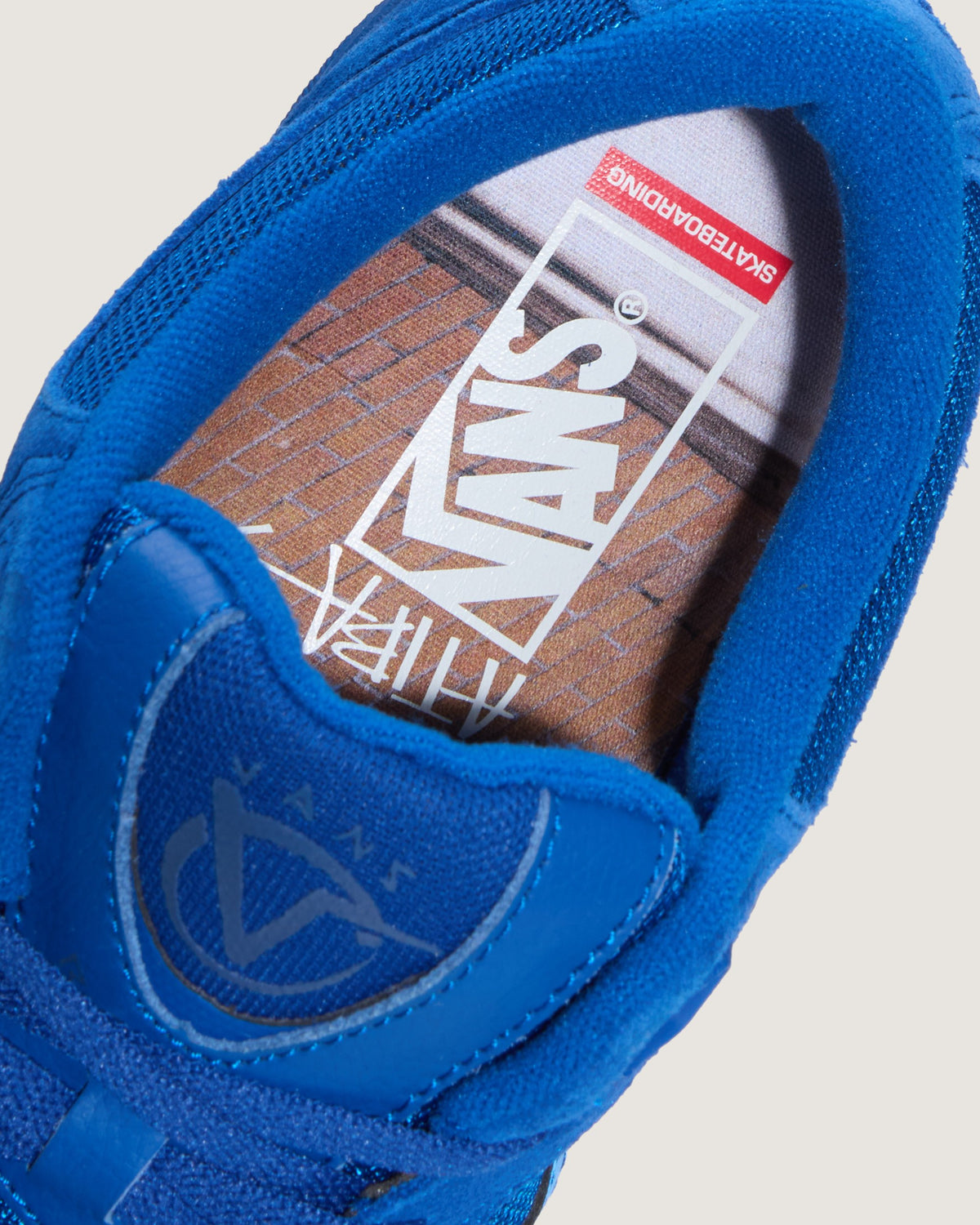 Close-up of a blue Vans slip-on shoe showing the inner side with the Vans logo on the insole and a skateboard graphic.