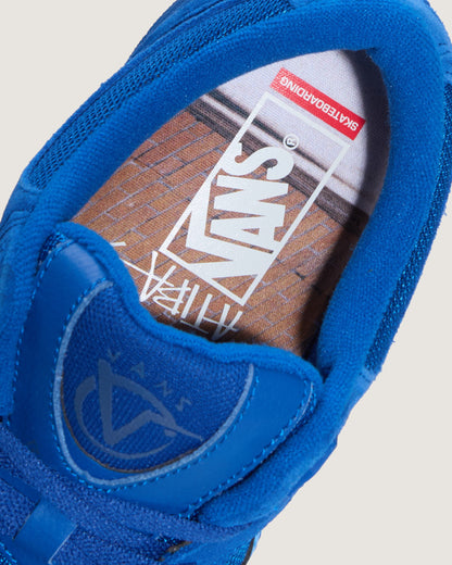 Close-up of a blue Vans slip-on shoe showing the inner side with the Vans logo on the insole and a skateboard graphic.
