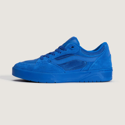 A single low-top sneaker in a vibrant royal blue suede and mesh material, shown from a side profile against a light beige background.