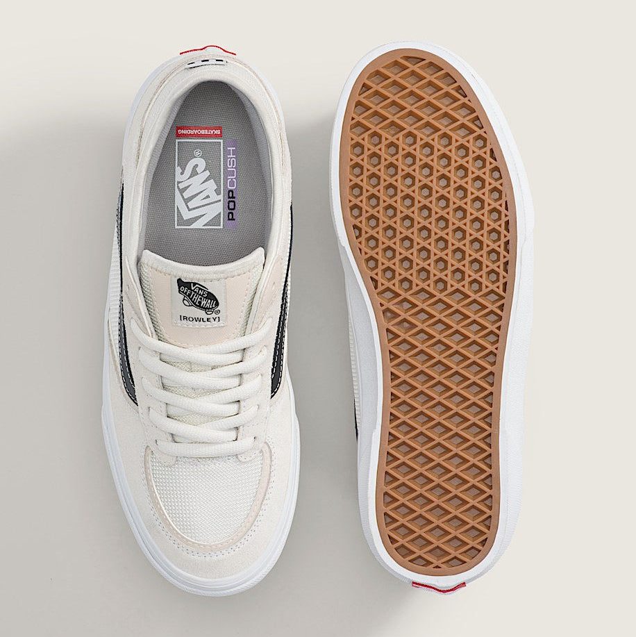 A pair of Vans Skateboard Classic sneakers shown from a top-down view, displaying the white side profile and the brown textured waffle-patterned sole on a light beige background.