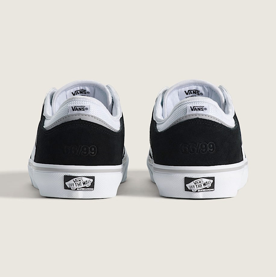 Black and white Vans sneakers on a light beige background