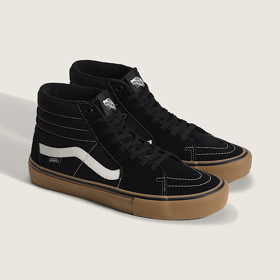 Black high-top sneakers with white stripes and brown soles on a light gray background