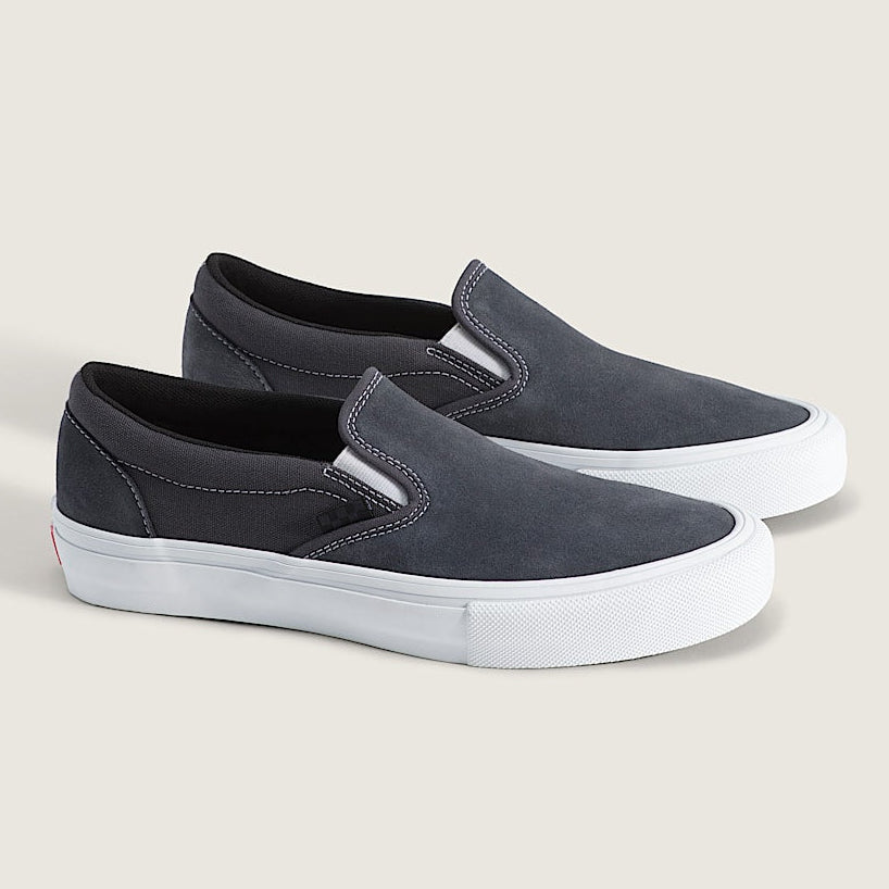 A pair of slip-on platform sneakers in dark gray suede with thick white platform soles, shown on a light beige background.