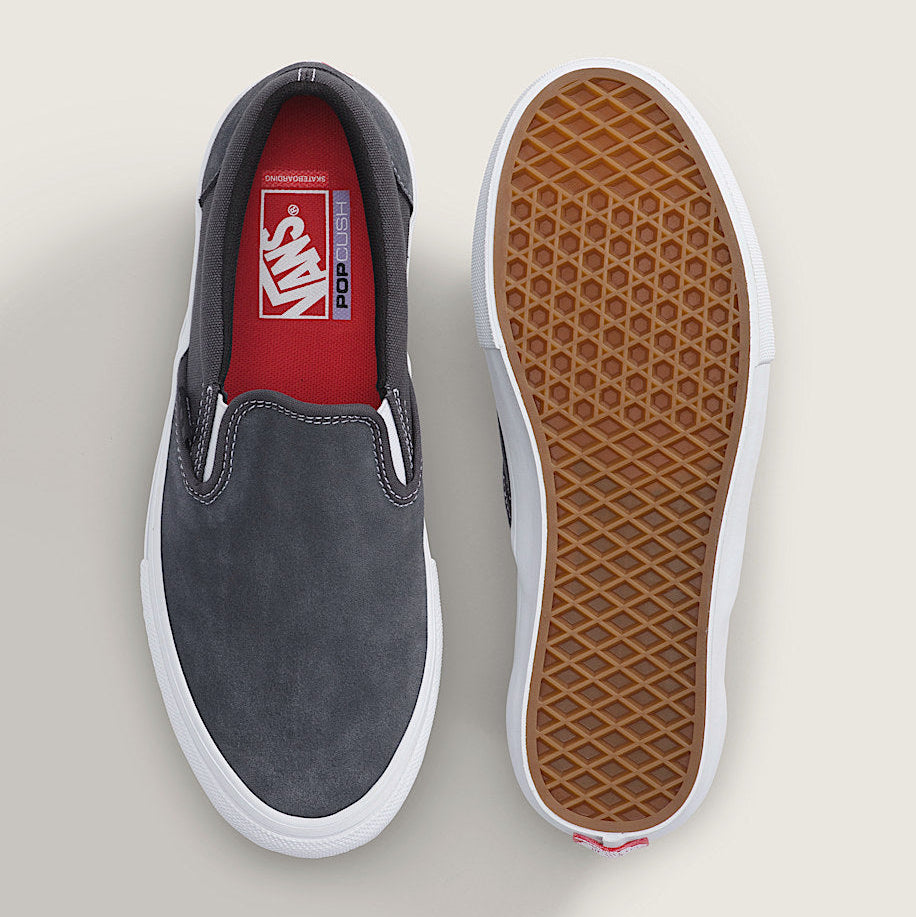 A pair of Vans slip-on sneakers shown from above, with one shoe displaying the dark gray suede upper and red interior, and the other showing the brown waffle-patterned outsole.