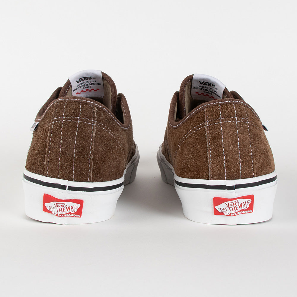 A pair of Vans platform sneakers shown from the back, featuring a brown suede upper, white platform soles, and the signature red Vans logo patch on the heel.